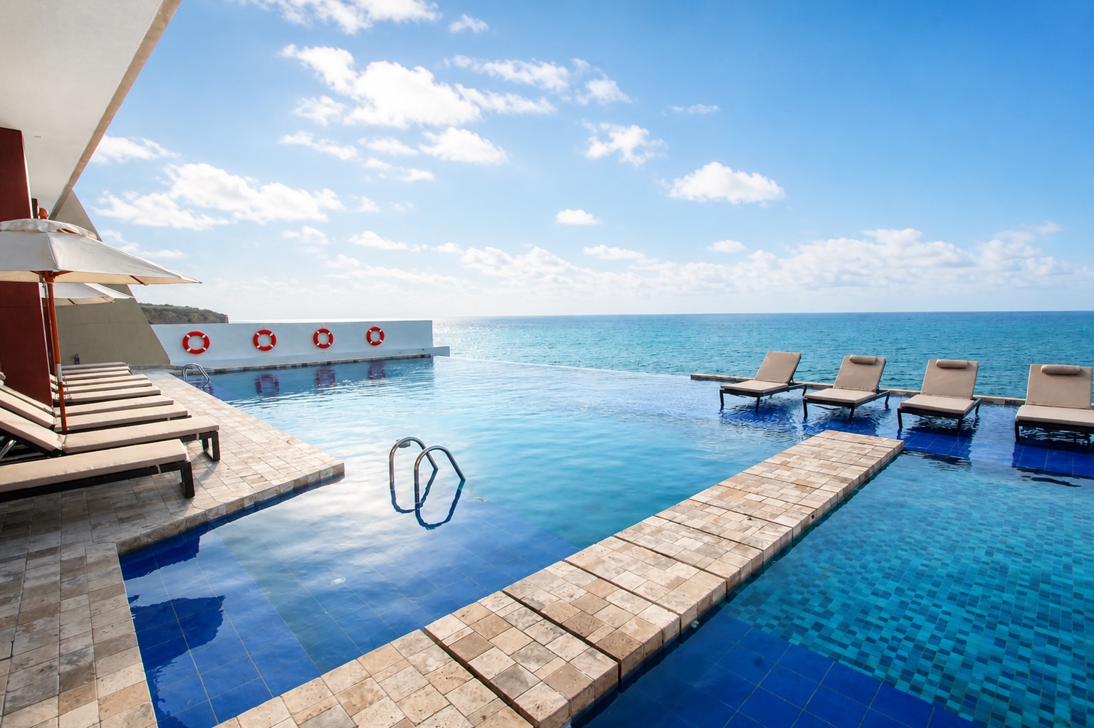 Resort infinity pool with ocean-facing sun loungers at Poseidon Manta