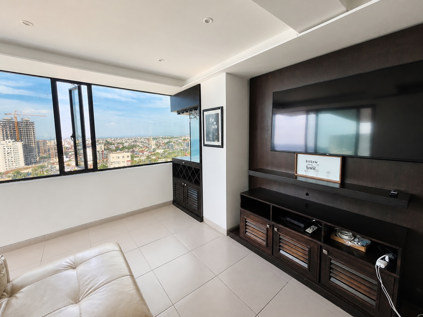 Bright living room with city views and entertainment center at Poseidon Manta condo