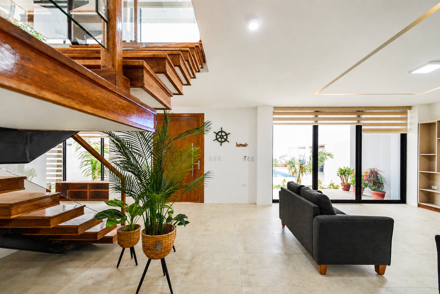 Open living area with a floating wood staircase and views toward the pool