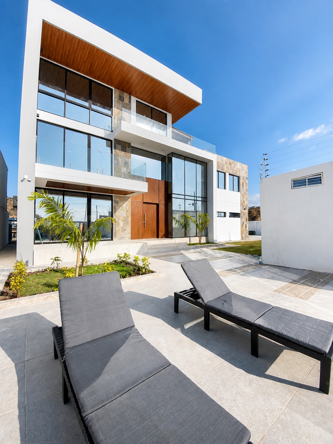 Poolside sun loungers facing the modern Santa Marianita oceanfront villa