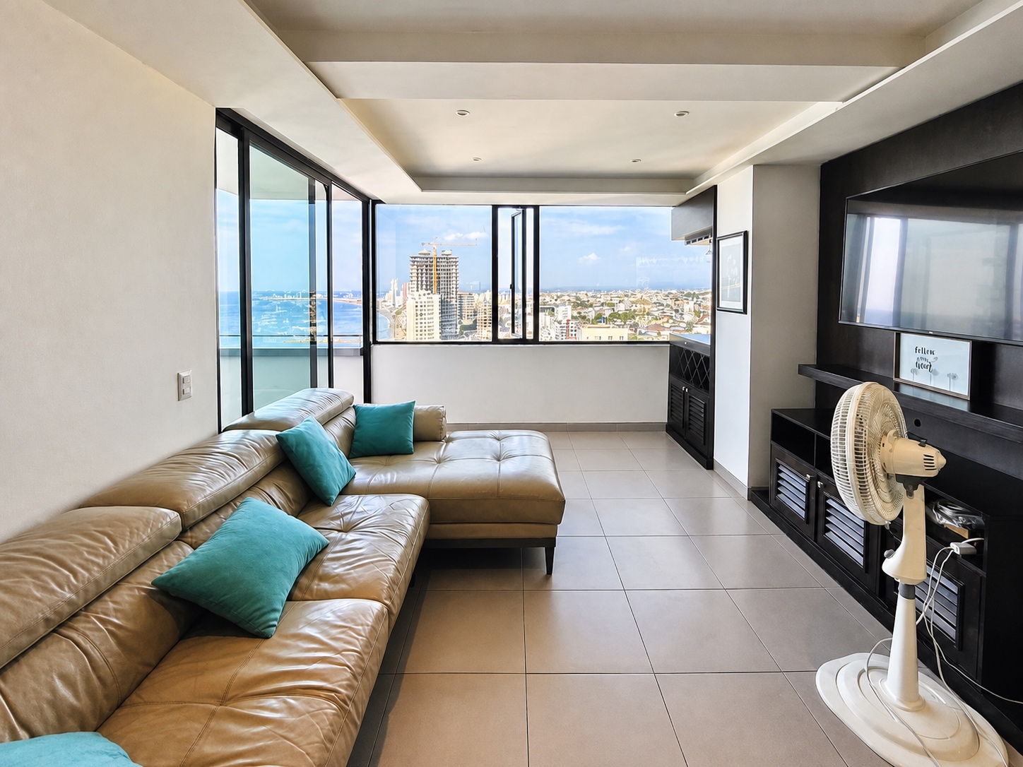 Spacious living room with panoramic ocean and city views at Poseidon Manta Resort