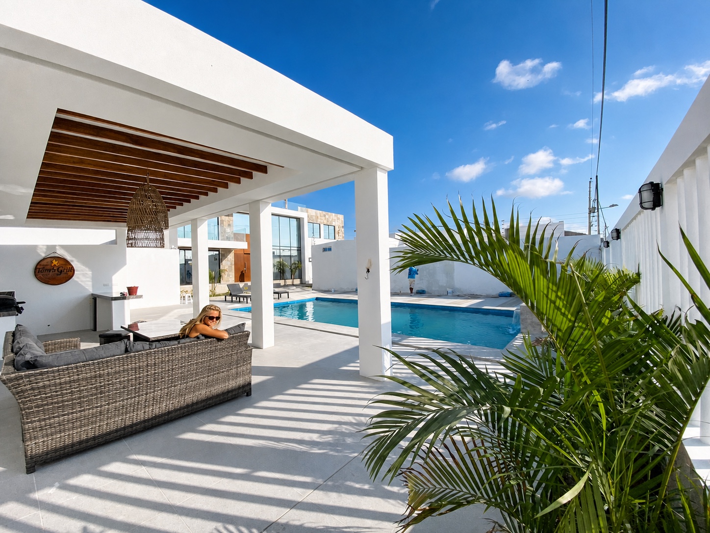 Covered poolside lounge with outdoor seating and tropical landscaping