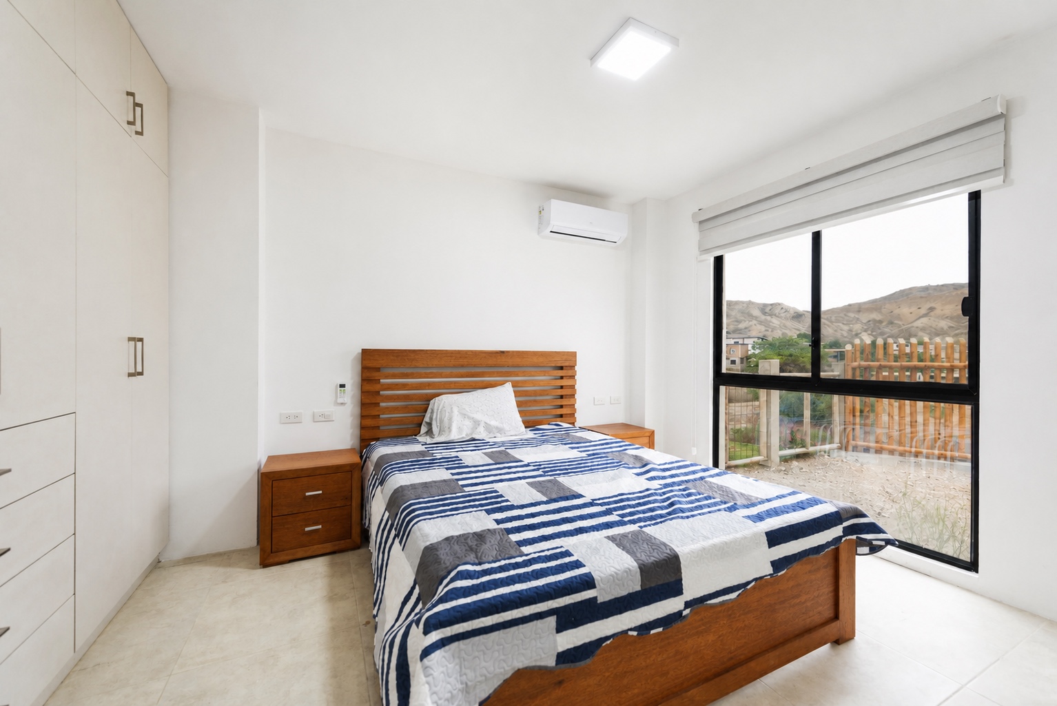 Bright guest bedroom with built-in storage and hillside views