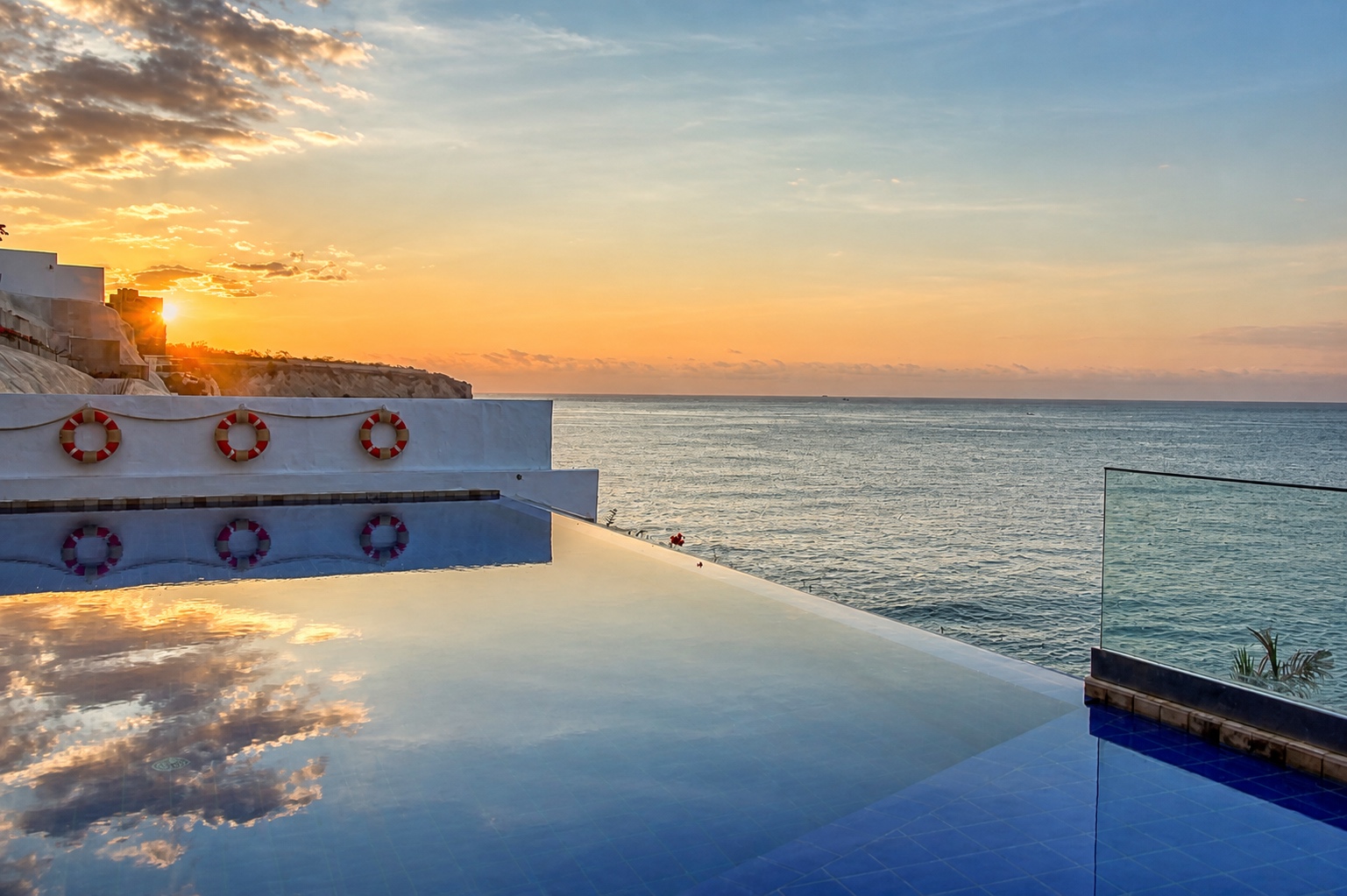 Oceanfront infinity pool reflecting a golden sunset at Poseidon Manta Resort