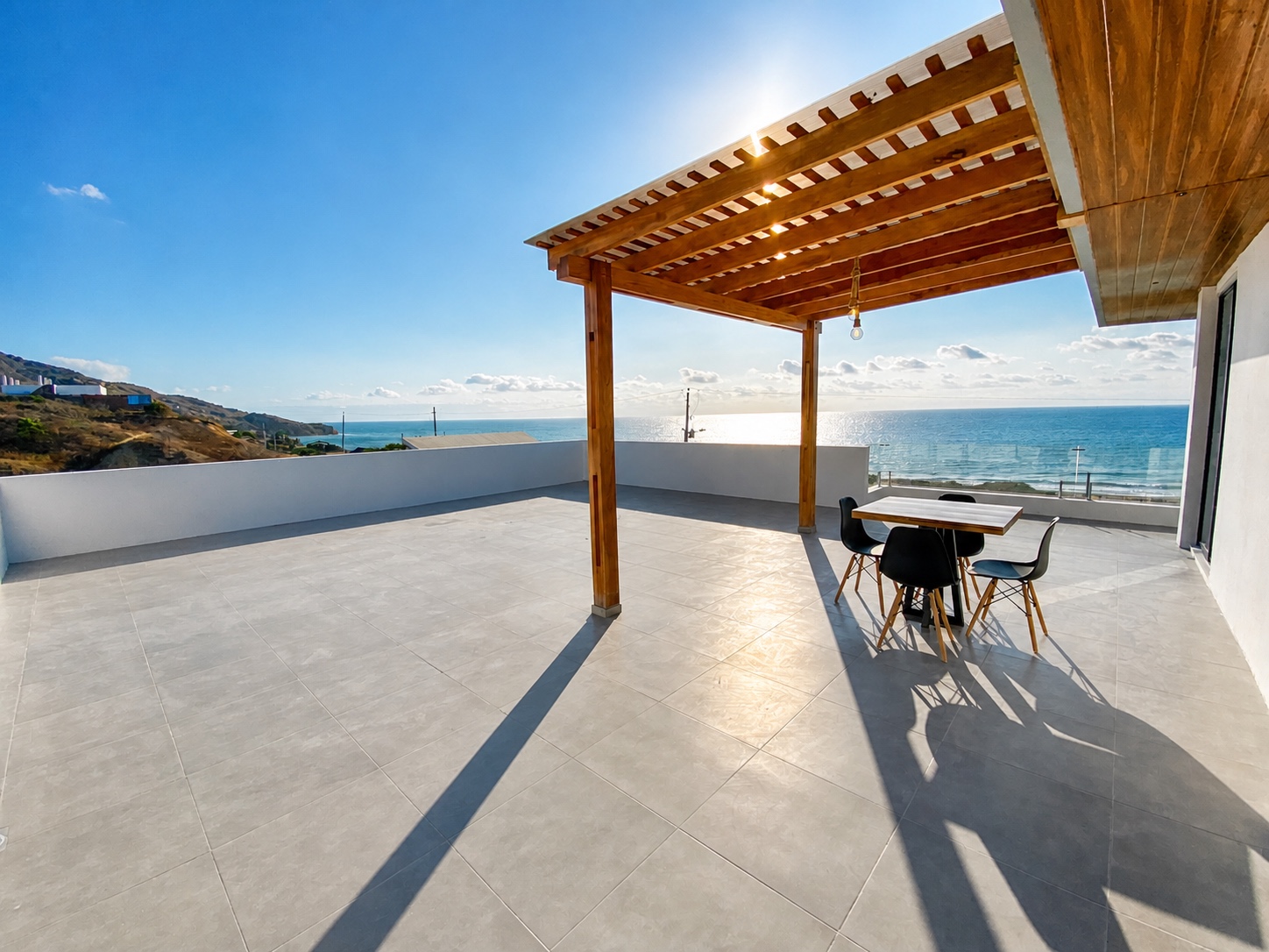 Rooftop terrace with a shaded dining table and panoramic Pacific Ocean views