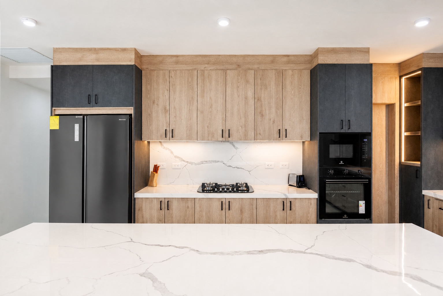 Modern kitchen with wood cabinetry, stone counters, and black appliances
