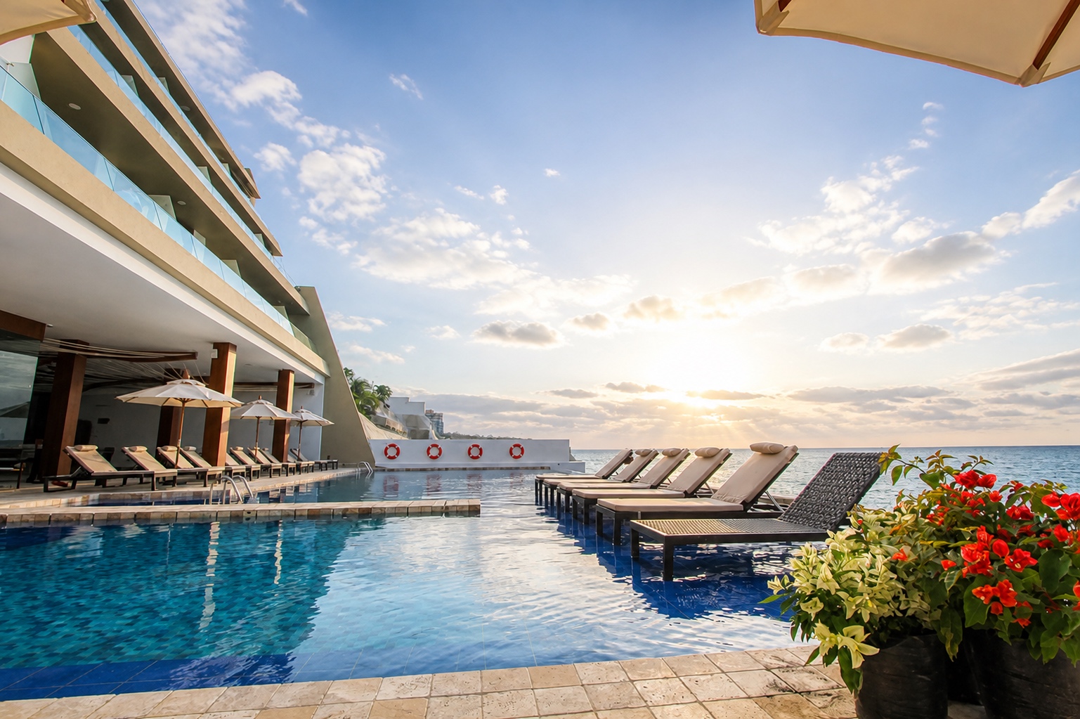 Poseidon Resort oceanfront infinity pool with loungers at sunset