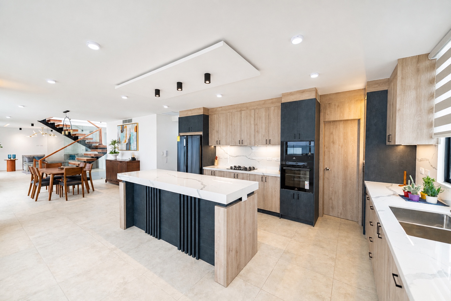Wide view of the open-plan kitchen, dining room, and wood staircase