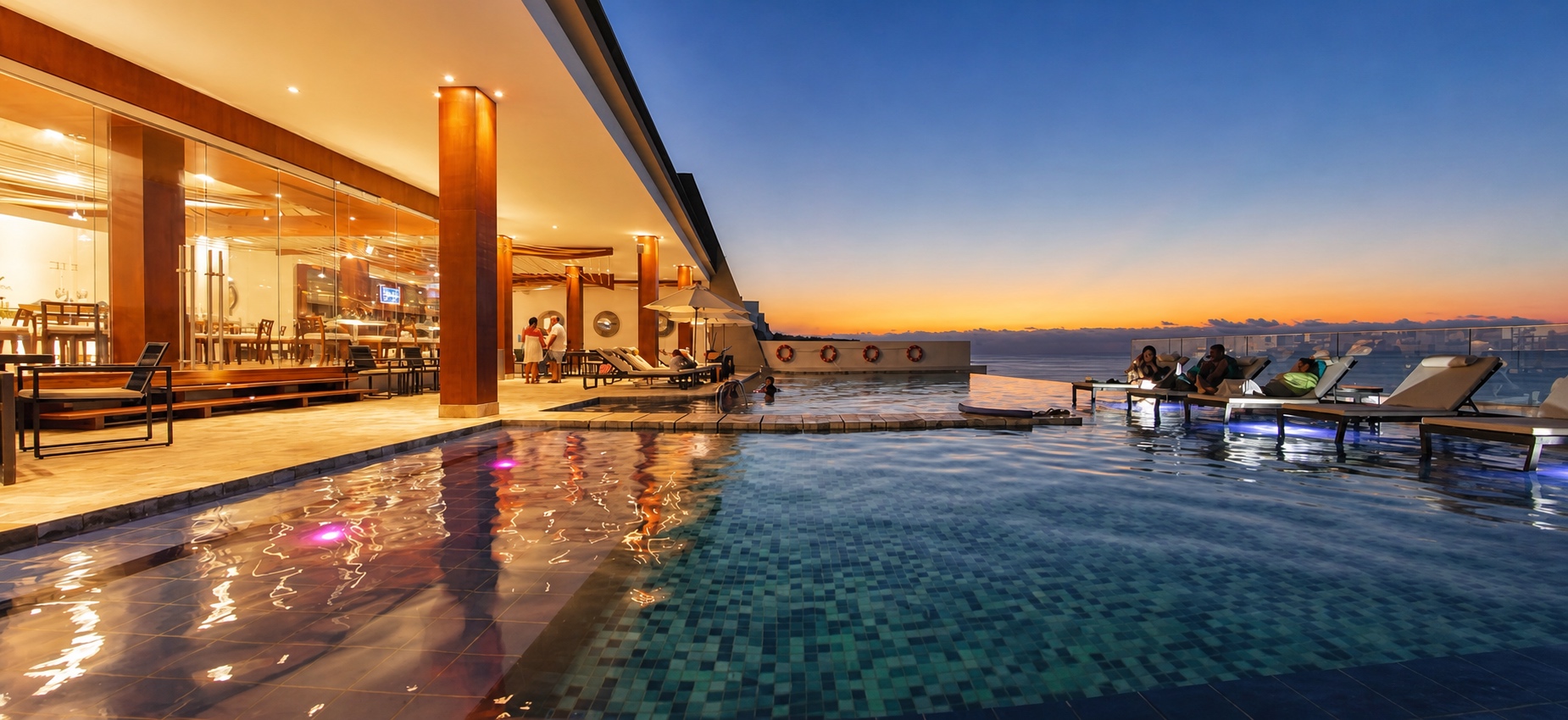 Poseidon Resort pool deck and restaurant at dusk overlooking the Pacific